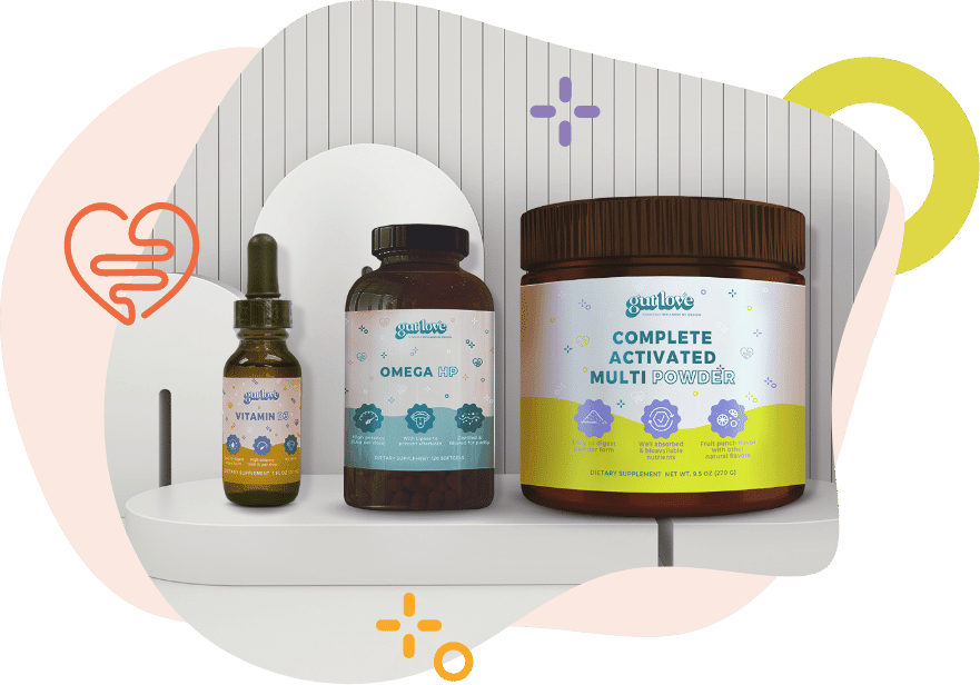 Three Gut Love IBD Supplements – Vitamin D3, Omega HP, and Complete Activated Multi Powder – sit in a row propped up by wooden shapes